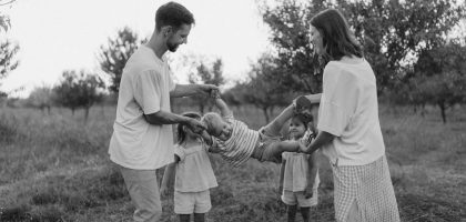 Family playing with child in grassy field