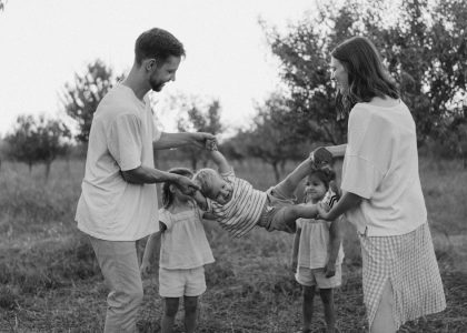 Family playing with child in grassy field